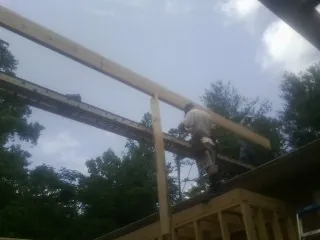 Carpenter setting a ridge beam over a new addition frame — Ice Dam Removal by Roofing Brothers in Shaw Afb