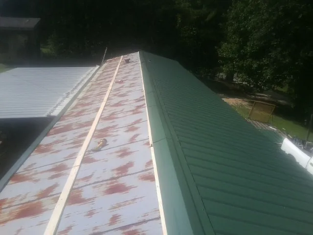 Old rusted panels beside newly installed green metal roofing — Wind Damage Roof Repair by Roofing Brothers in Shaw Afb