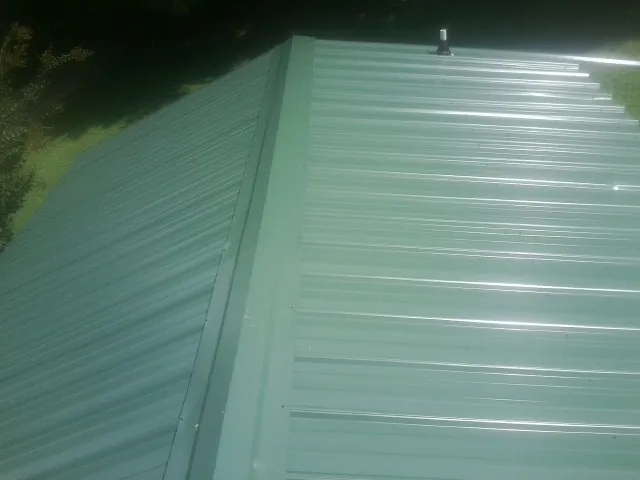 New green metal panels meeting at the ridge of a roof — Flat Roof Repair work by our crew in Shaw Afb