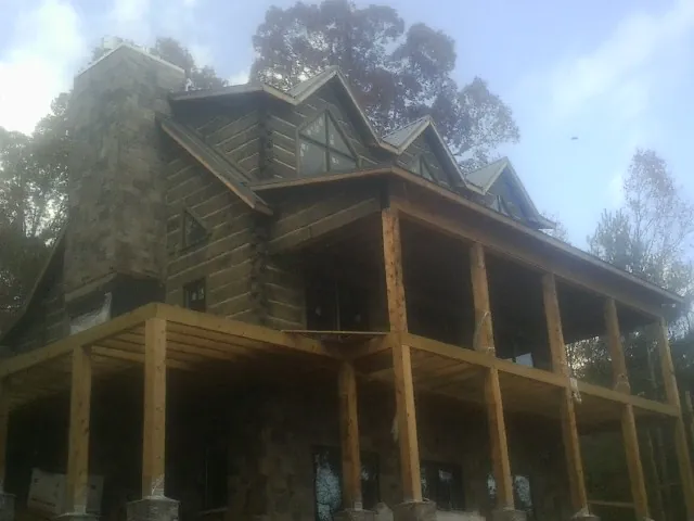 Stone chimney and dormers on a large log home with a timber porch in Shaw Afb