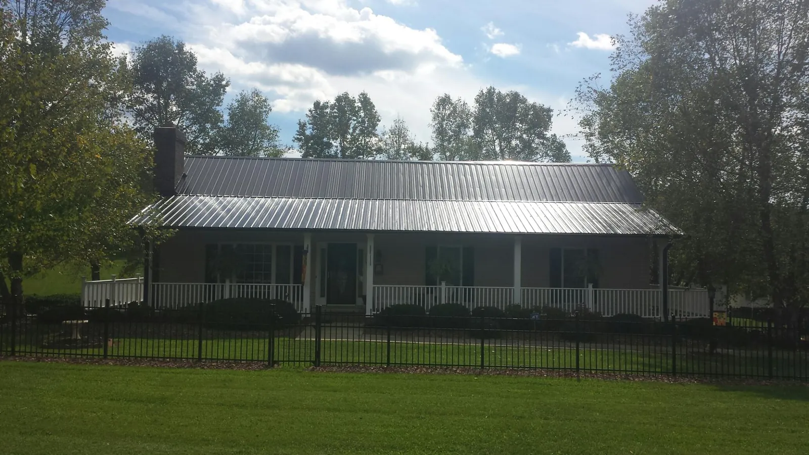 Gray metal roof on a brick ranch with a full width front porch — Gutter Guard Installation work by our crew in Shaw Afb