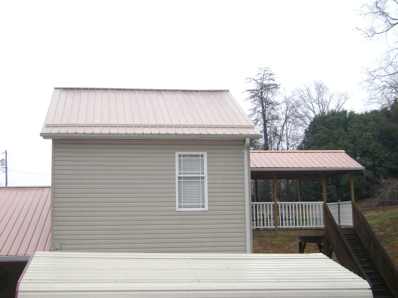 Tan metal roofs on a two story addition and attached porch, from a Roof Replacement job in Shaw Afb
