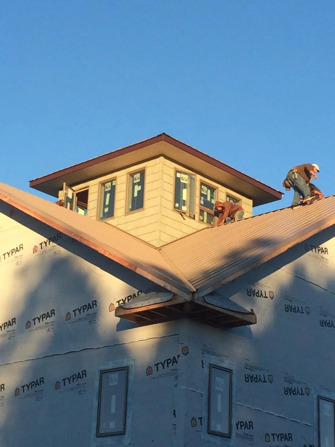 Roofers working around a rooftop cupola on a new metal roof at sunset — Roof Waterproofing in Shaw Afb by Roofing Brothers